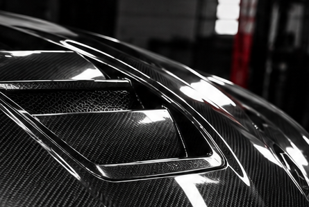 Glossy black vented carbon fiber hood close-up
